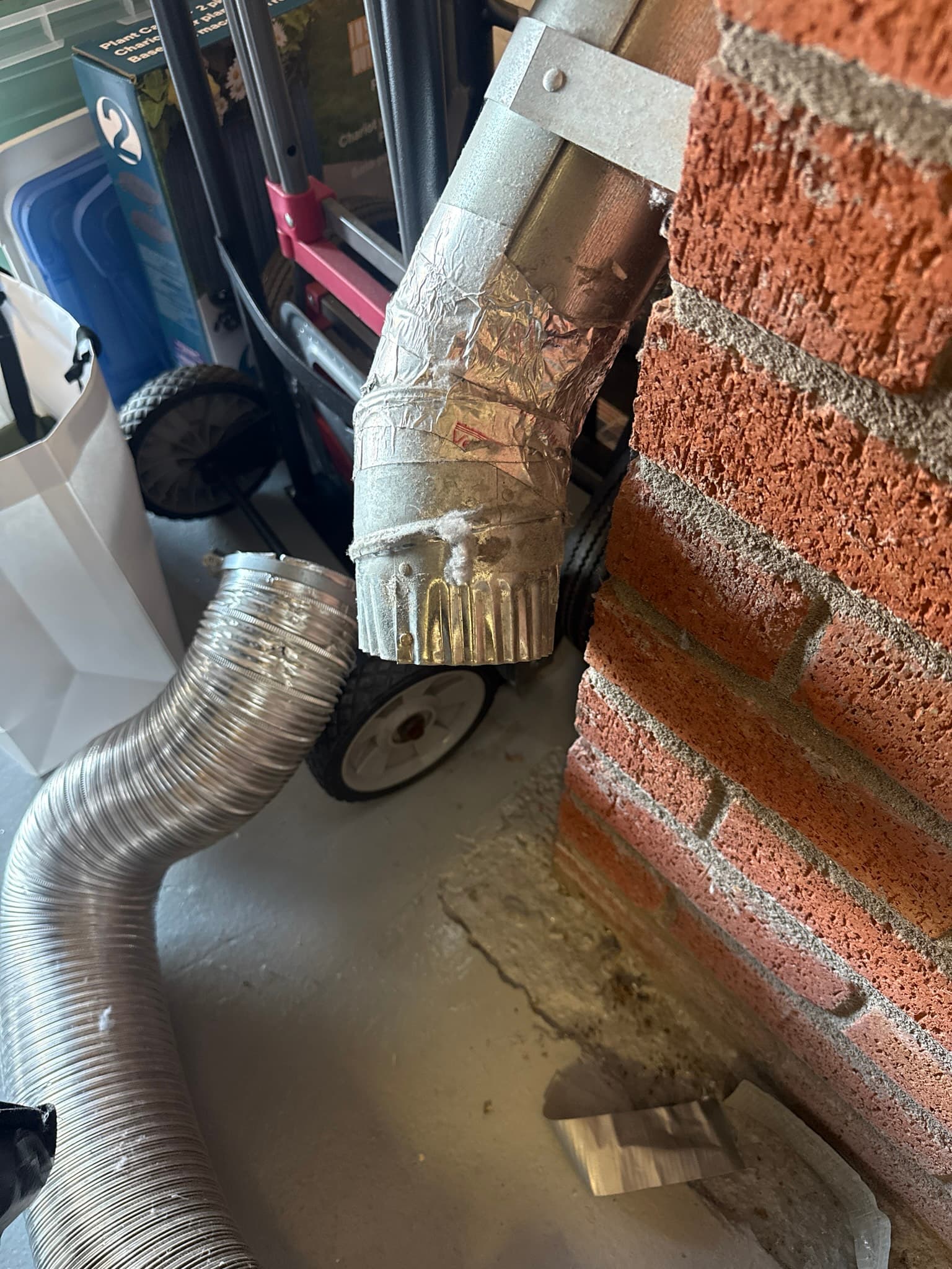 Exterior dryer vent termination cap on a brick wall with heavy lint and debris packed into the louvers and outer surfaces, severely restricting exhaust airflow