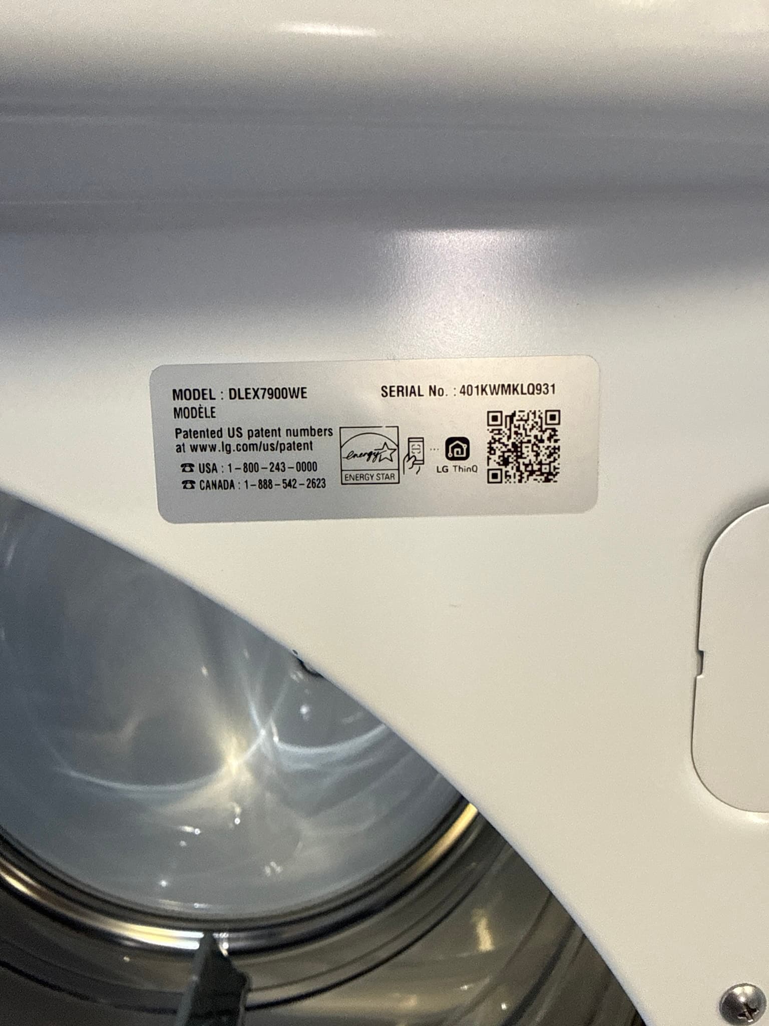 Manufacturer identification label on top of the LG clothes dryer, showing model number DLEX7900WE, serial number, and Energy Star certification. The dryer exterior appears clean and undamaged.