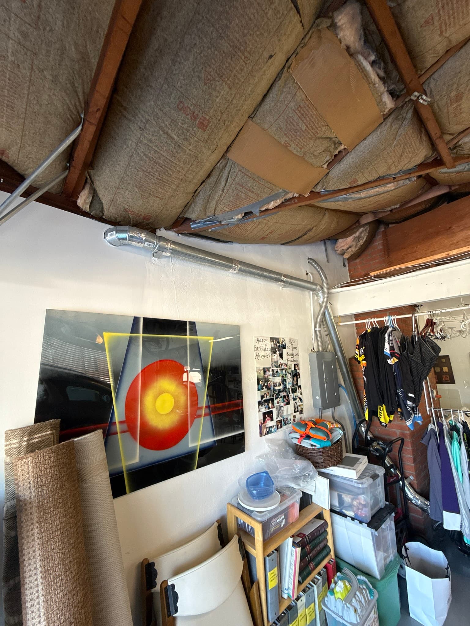 Interior garage view of a dryer exhaust duct run approximately 13 feet long, with a flexible metallic duct routed along the ceiling through multiple elbows before exiting the structure