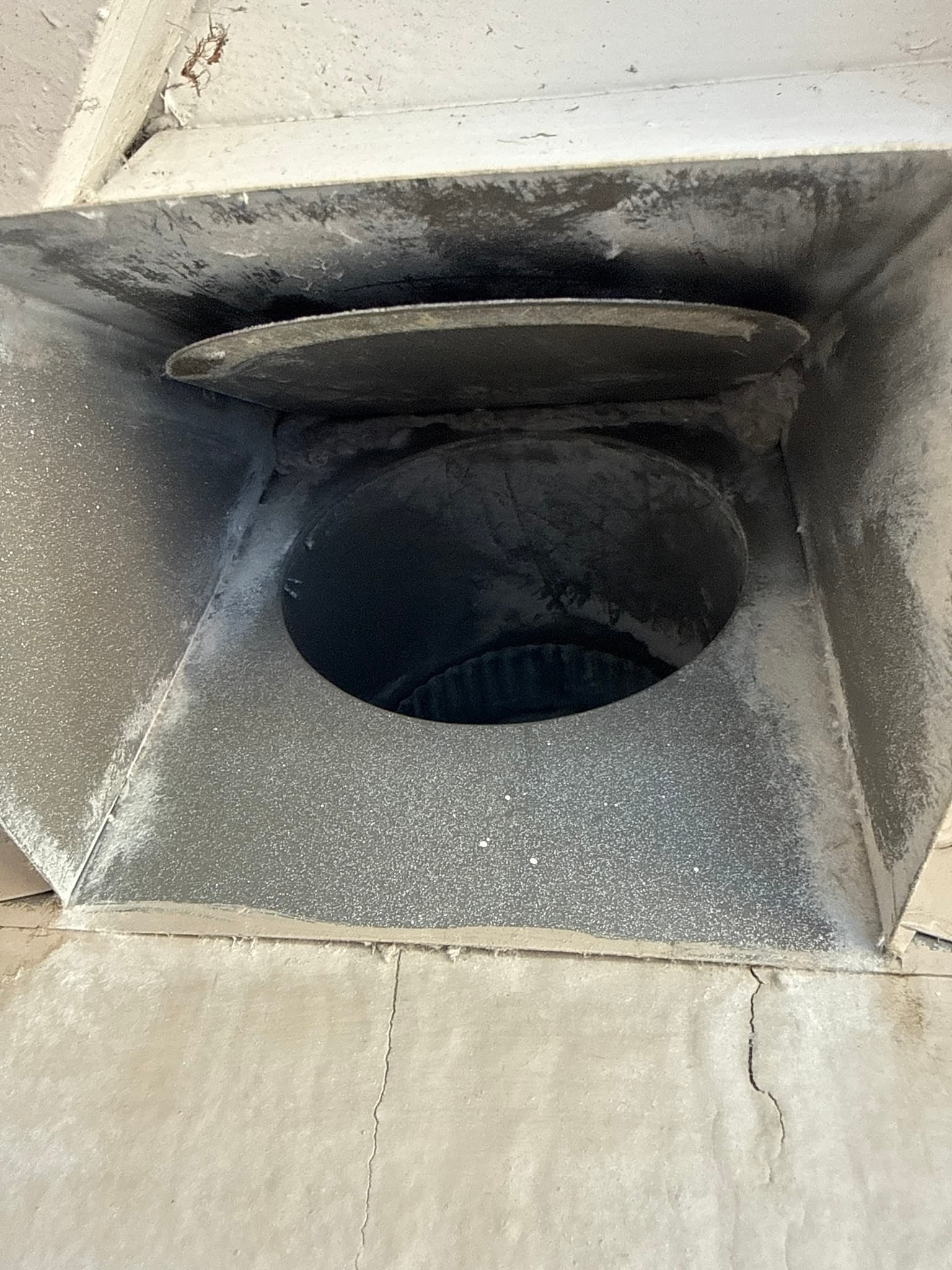 Exterior dryer vent opening showing severe lint blockage inside the duct and around the metal vent cap. Dark, compacted lint nearly fills the duct opening, and the surrounding masonry shows surface deterioration.