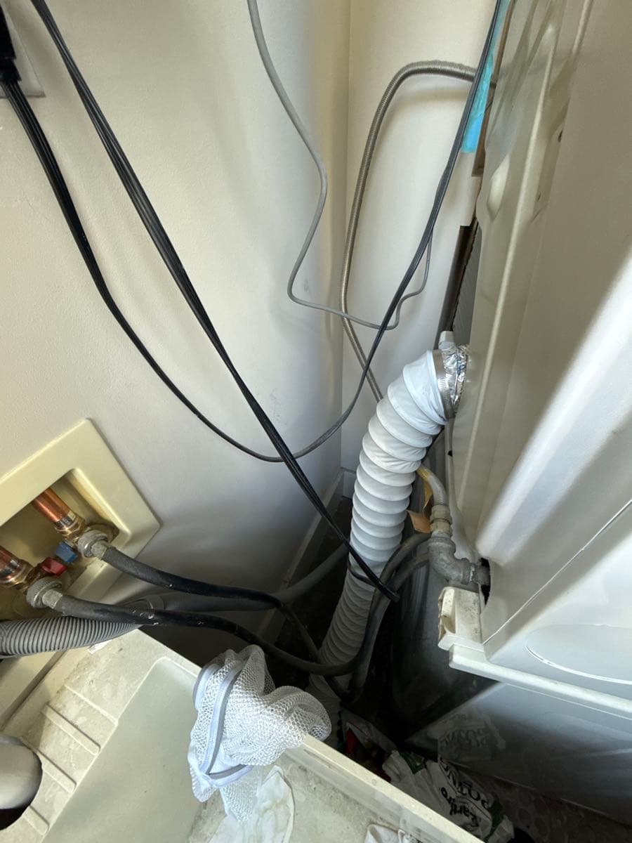 Before photo showing long Mylar flexible dryer transition duct approximately 9 feet in length connecting dryer to wall outlet