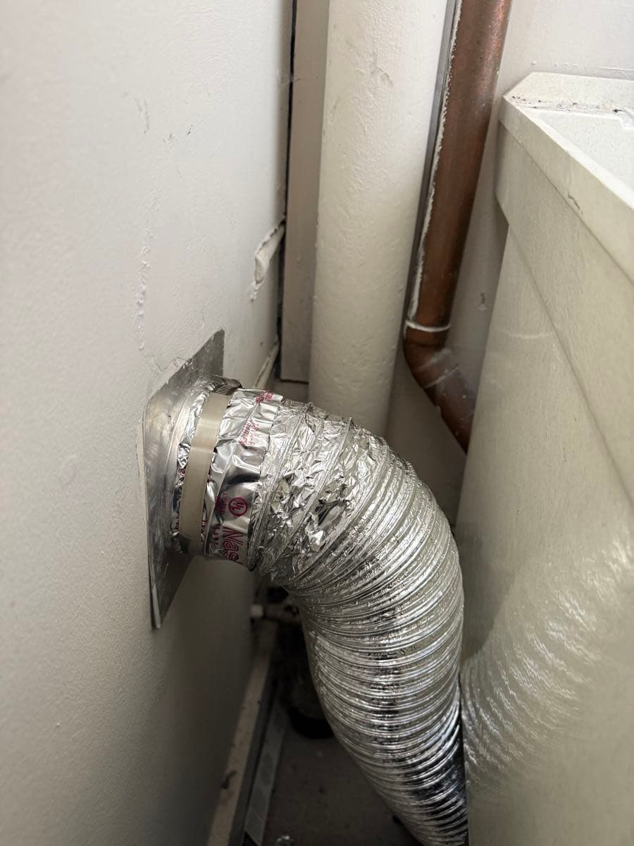 Close-up view of dryer vent ductwork connections and joint sealing work