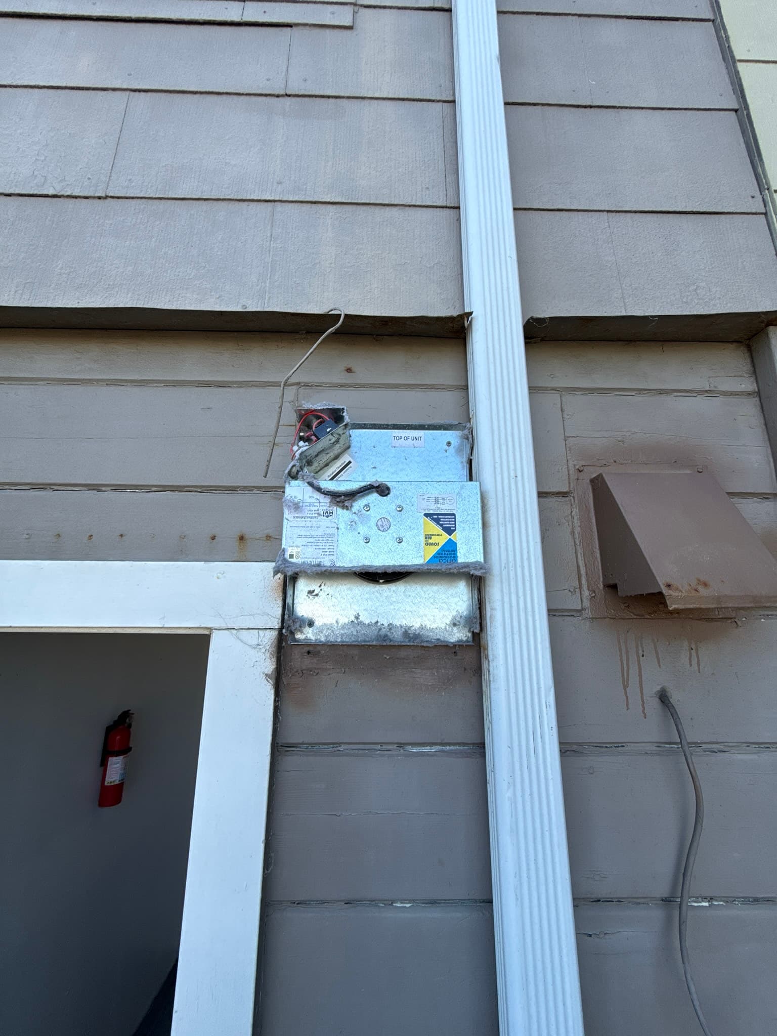 Close-up of the dryer exhaust duct connection at the back of a residential dryer in a garage