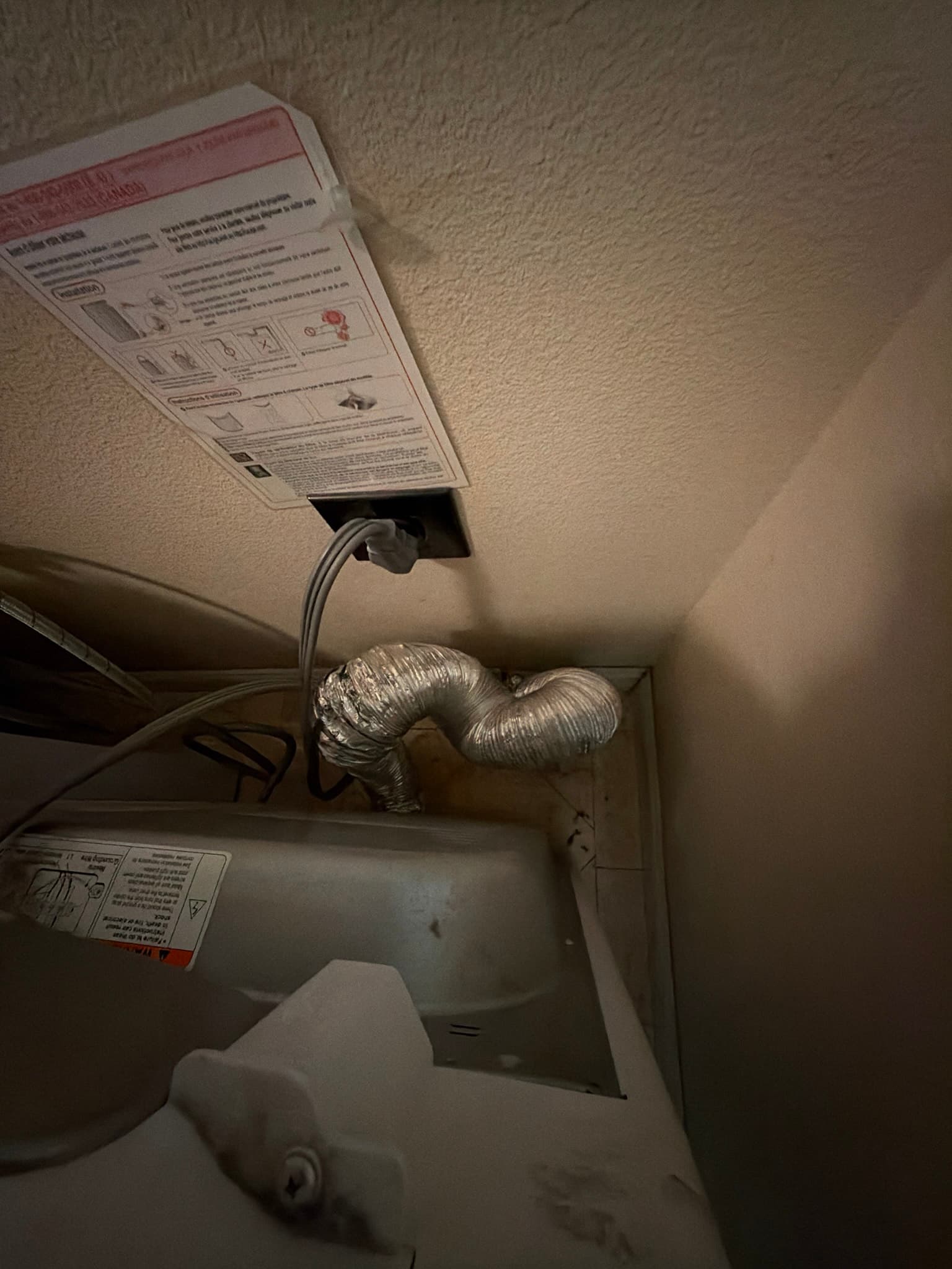 Dryer pulled away from the wall in a Cupertino laundry area, showing the old semi-rigid metal transition duct crushed and bent into tight folds behind the unit with heavy lint buildup along the run.