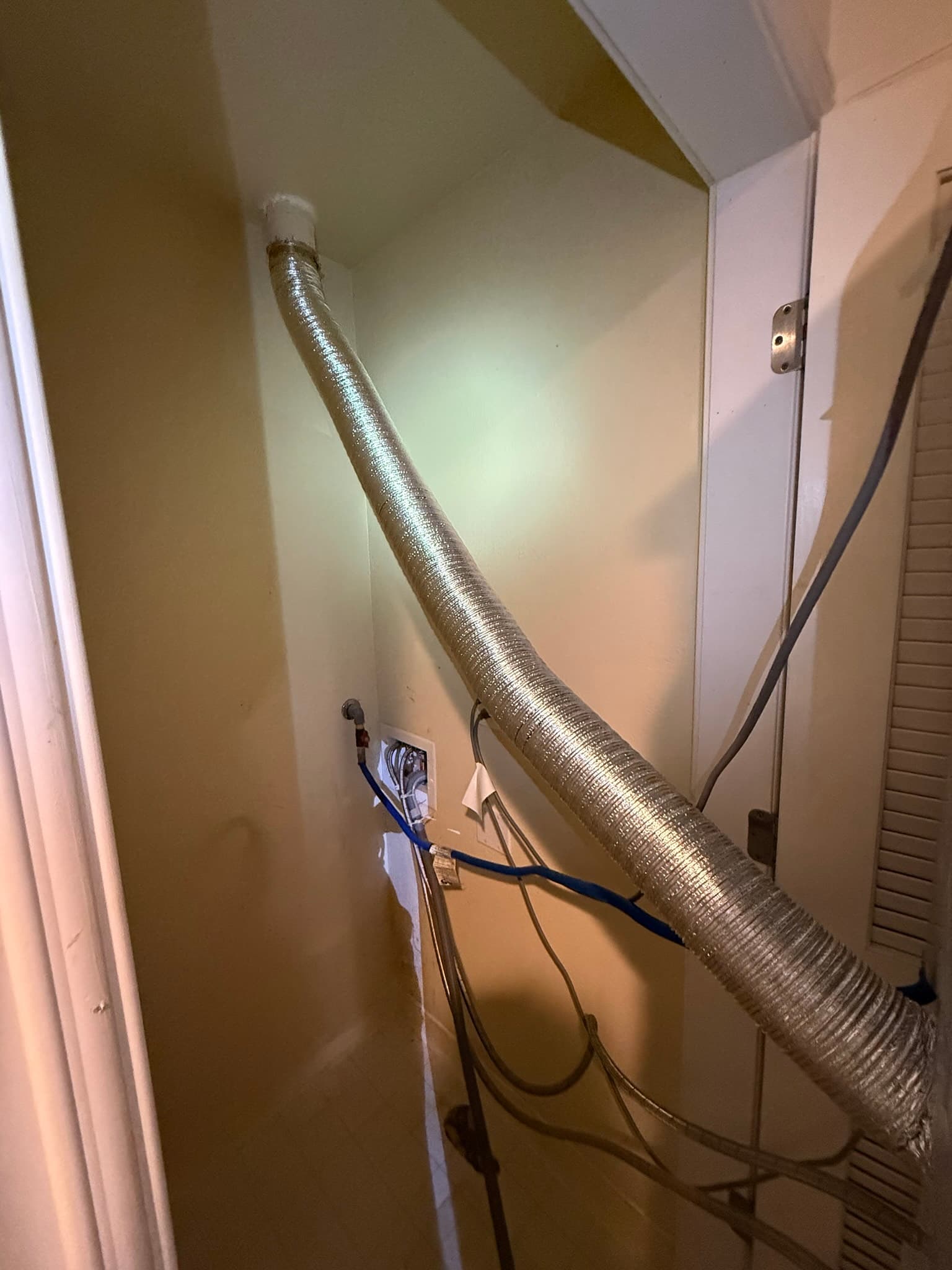 Newly installed UL 2158A-rated semi-rigid metal transition duct connecting a residential dryer to the wall exhaust port