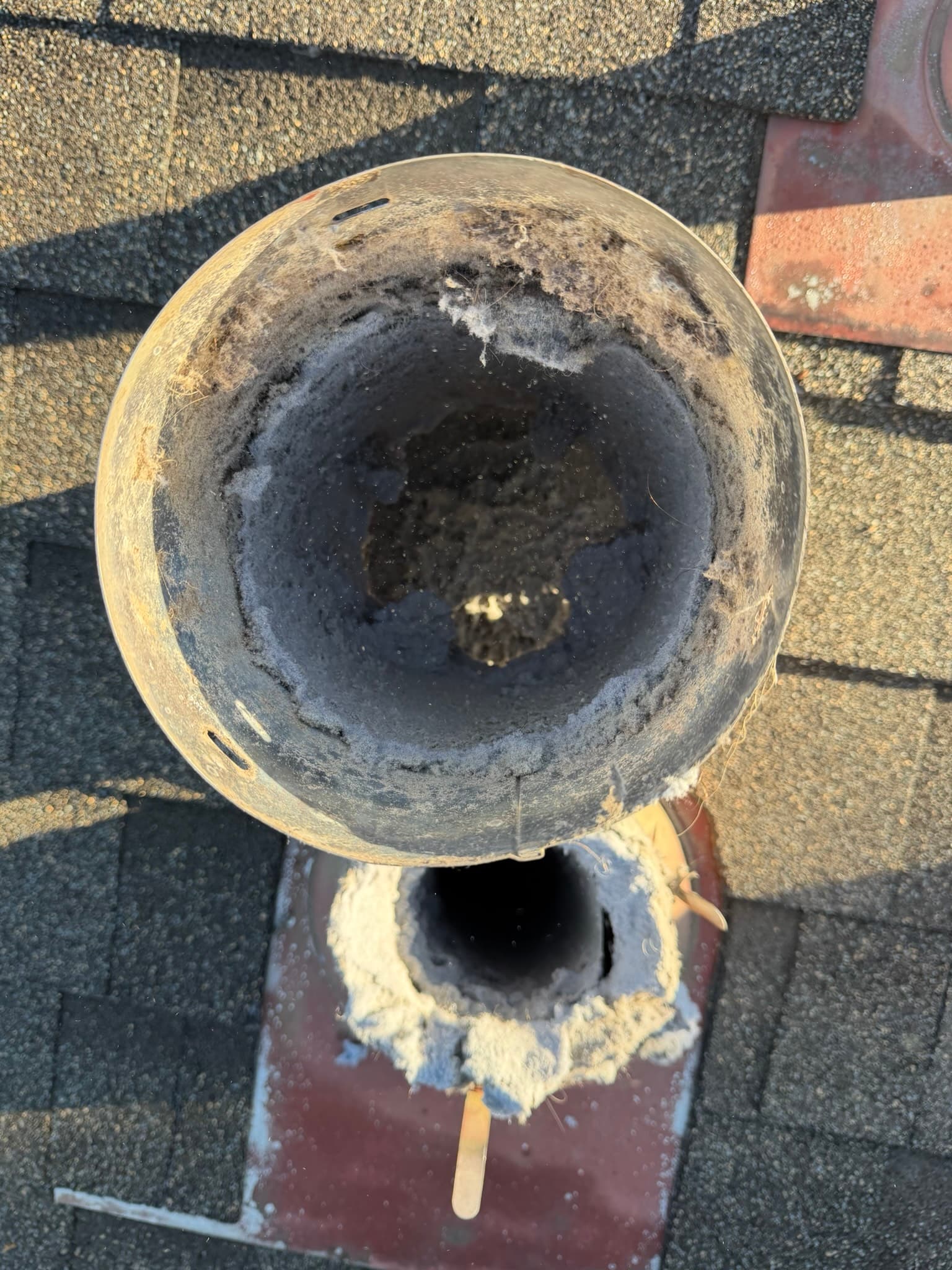 Roof-mounted exhaust hood interior coated with heavy lint accumulation around the outlet opening