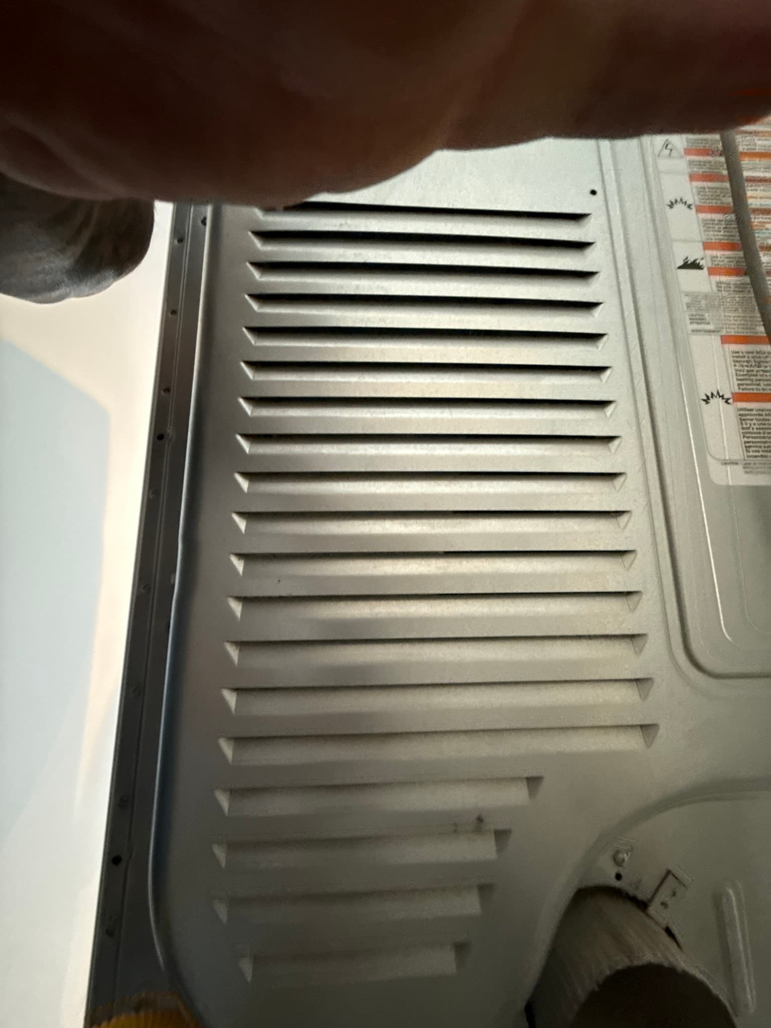 Close-up of an exterior dryer vent cap with horizontal aluminum louvers in clean condition, mounted flush against the exterior casing with no visible lint accumulation or blockage