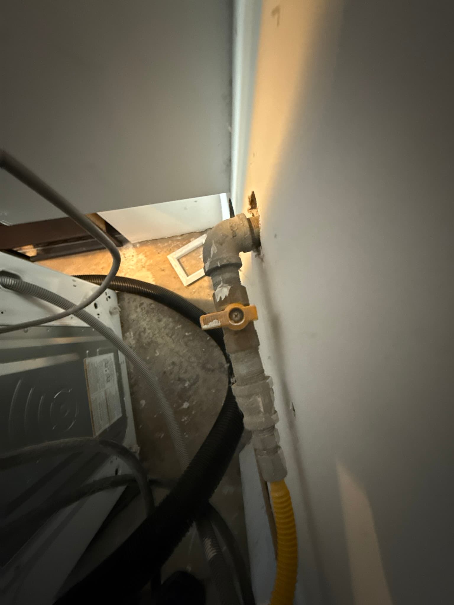 Dryer exhaust duct connection showing a heavily soiled flexible transition duct with lint and dust accumulation and a corroded metal elbow fitting secured with a hose clamp