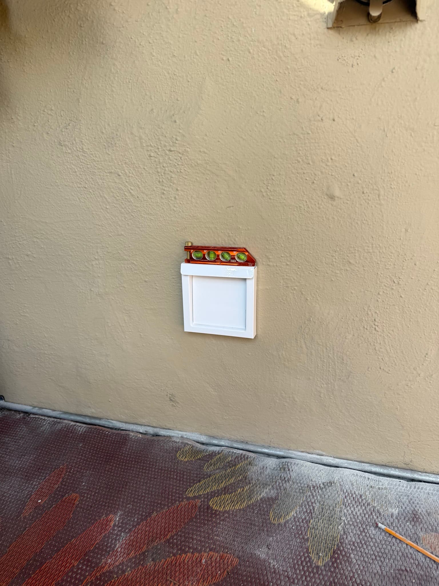 InOvate flush-mount dryer vent hood installed on stucco exterior siding, showing the silicone-backed perimeter seal where the hood sits flush against the wall surface