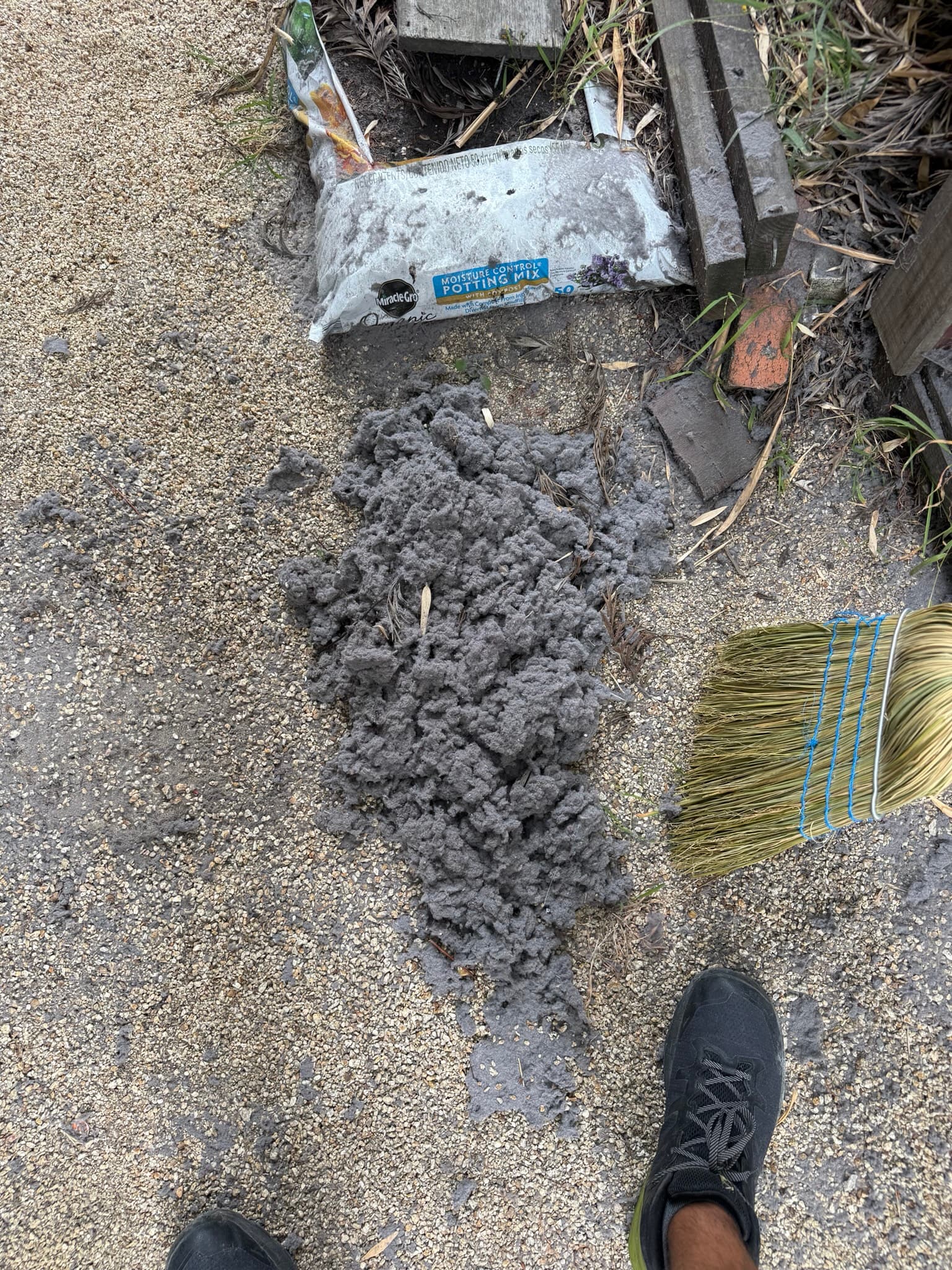 Exterior dryer vent wall cap with a large extracted pile of compacted gray lint laid out on the ground below the discharge opening, showing the severity of the blockage before cleaning