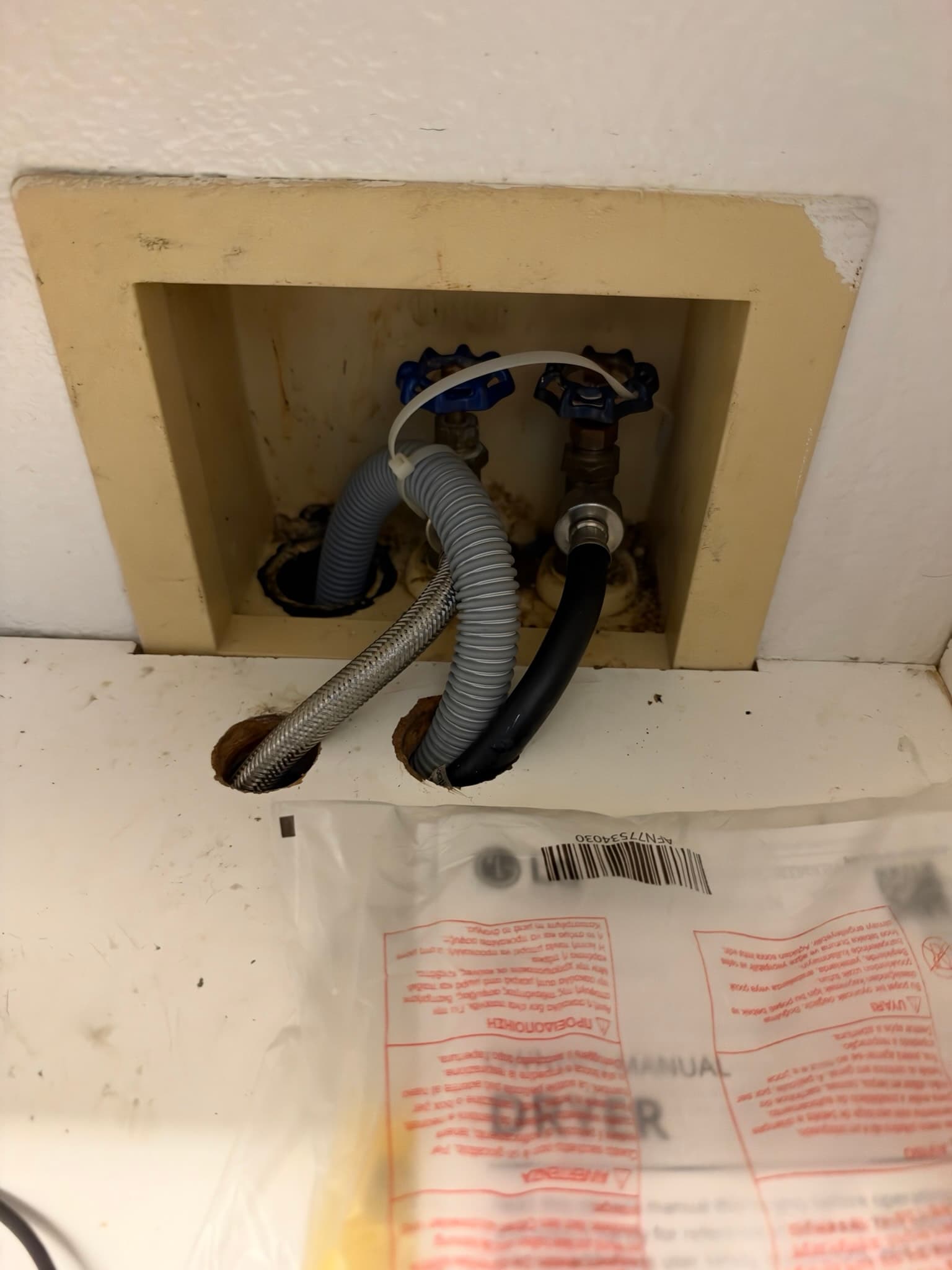 Recessed wall supply box showing two blue-handled shutoff valves connected to a braided stainless supply line and a steam line feeding into the drain standpipe