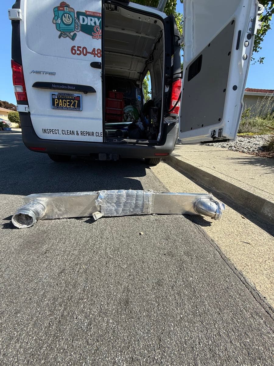 Professional dryer vent cleaning in progress using rotary brush equipment