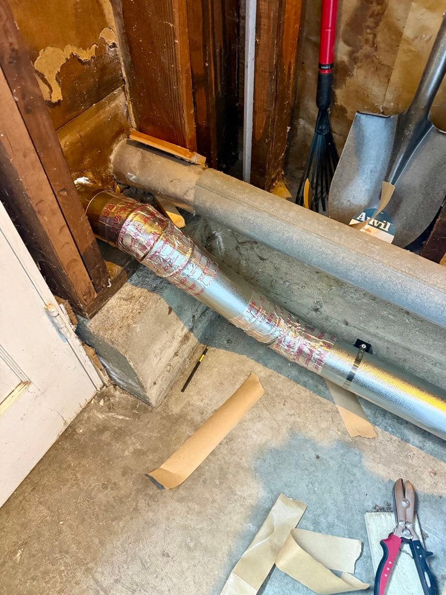 Final section of new dryer exhaust system with two 60-degree elbows mounted to foundation with bat clamps and stainless steel hose clamps