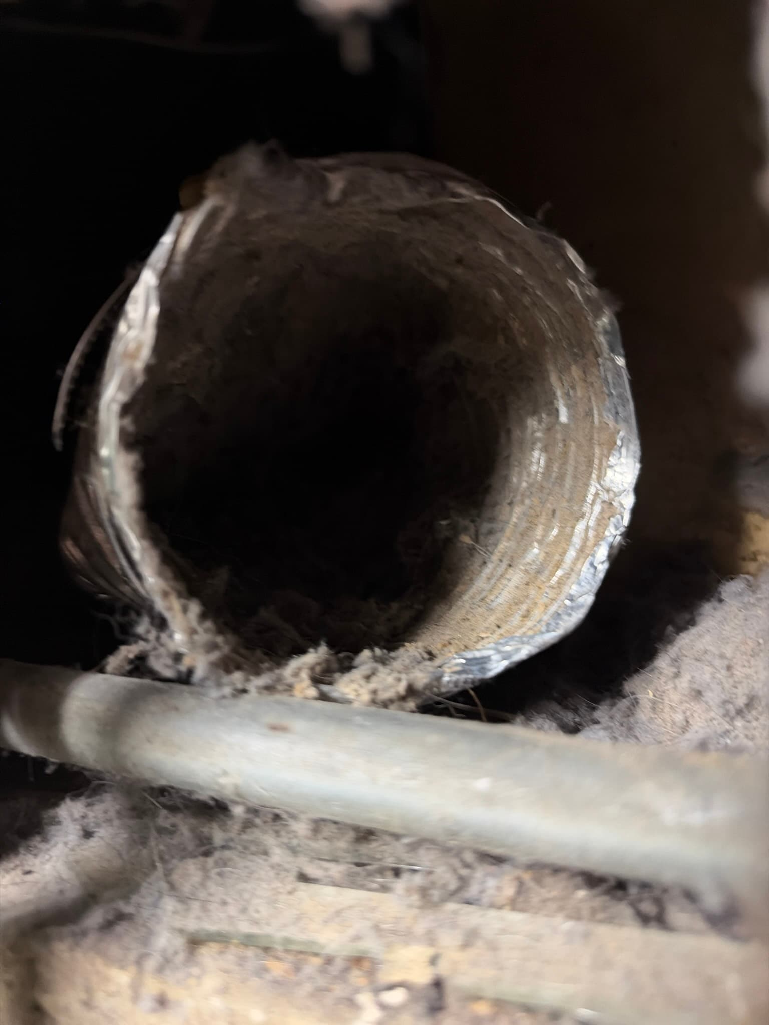 Open end of a transition duct section coated in heavy compacted lint along its interior walls before cleaning.