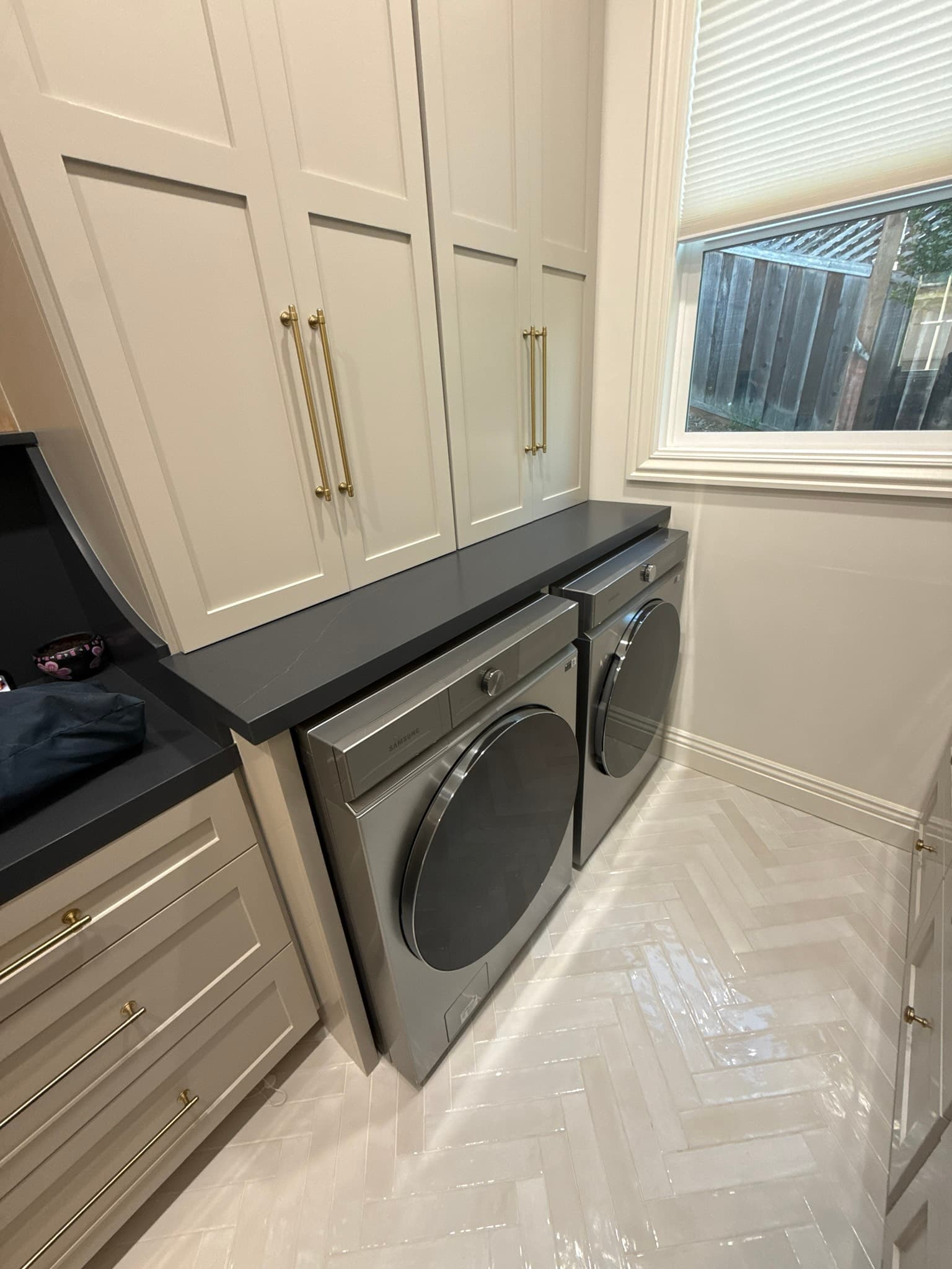 Renovated Los Altos laundry room with two front-load washers and dryers installed side by side beneath white custom cabinetry, showing the confined installation space that concealed serious dryer vent deficiencies behind the appliances