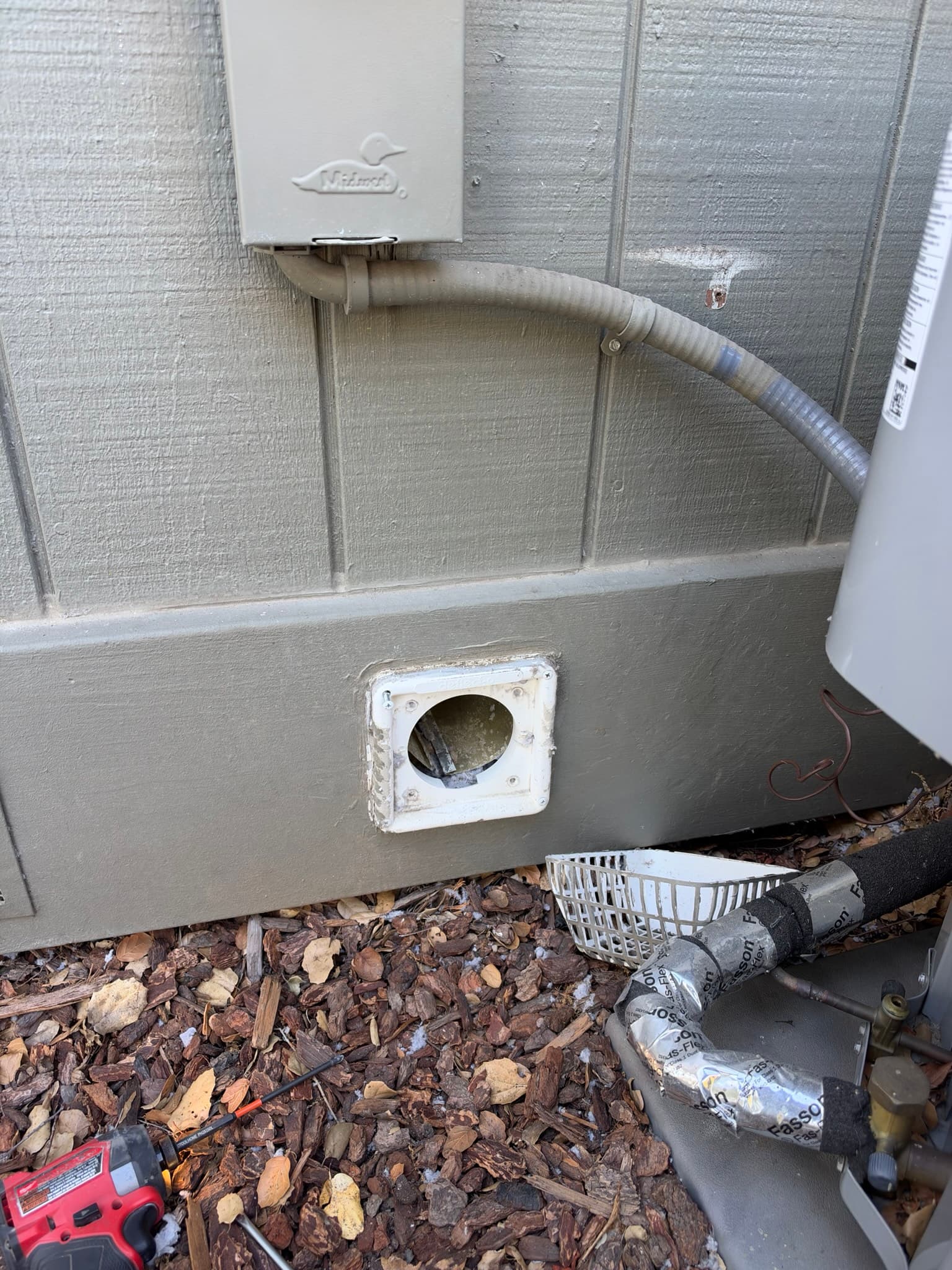 Close-up of the flush mount dryer wall vent screwed into siding with flexible metal transition duct connecting from above