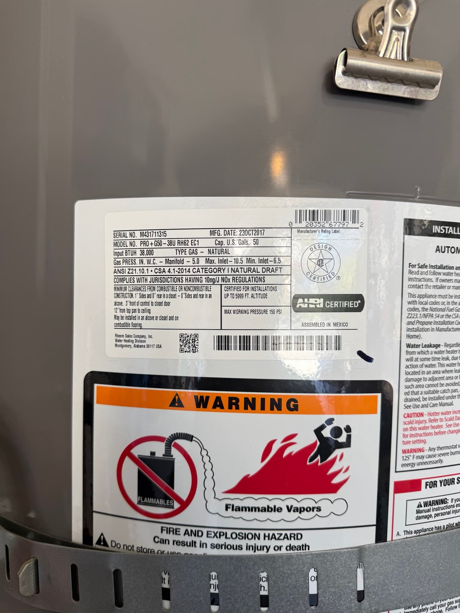 Manufacturer label and orange warning decal on a 50-gallon natural gas water heater, model PRO-plus-G50-38U RH2 EC1 manufactured in 2017, with fire and explosion hazard warnings for flammable vapors
