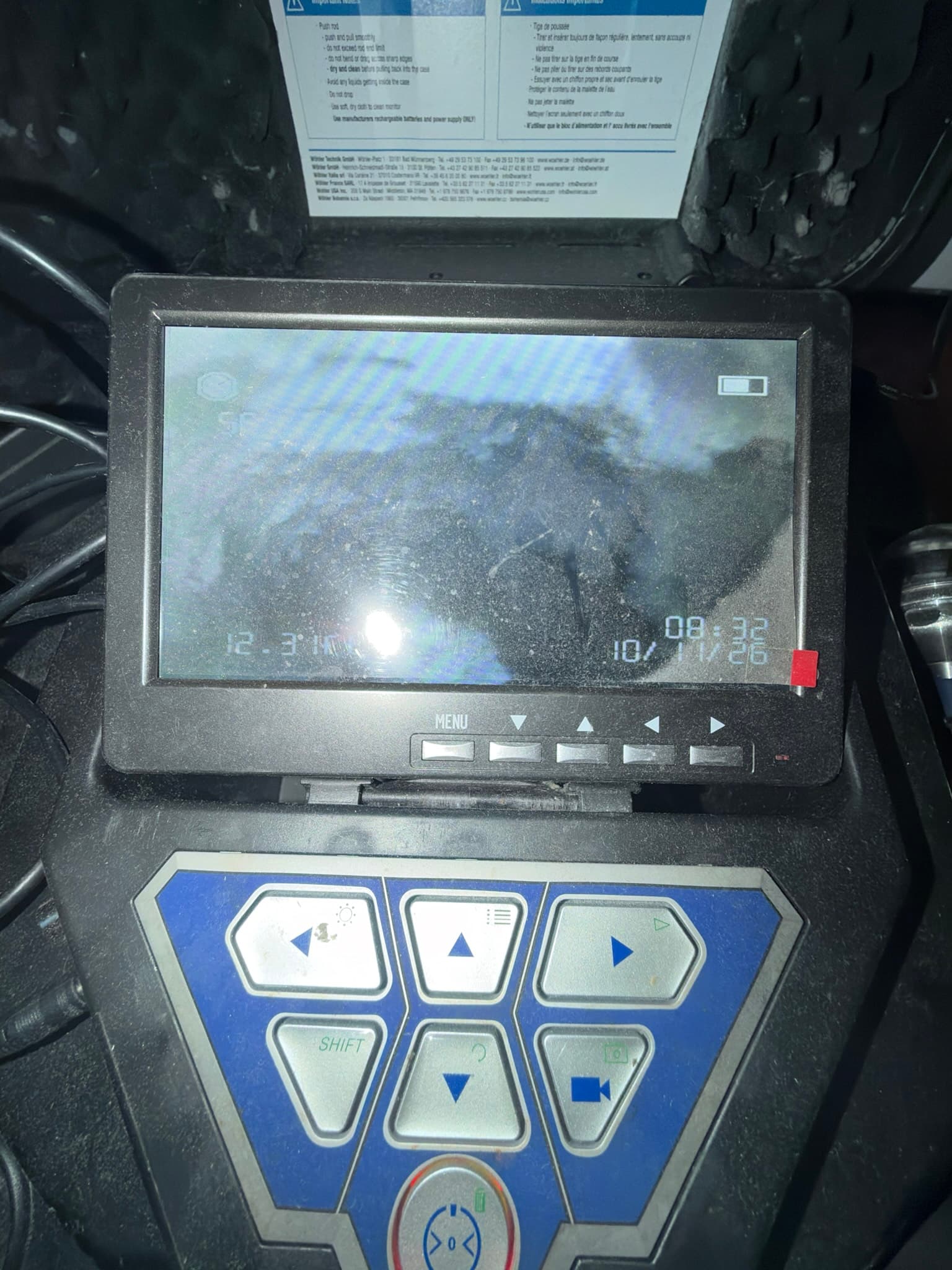 Inspection camera monitor displaying a timestamped feed from inside the duct, showing heavy dark lint buildup coating the interior surface.