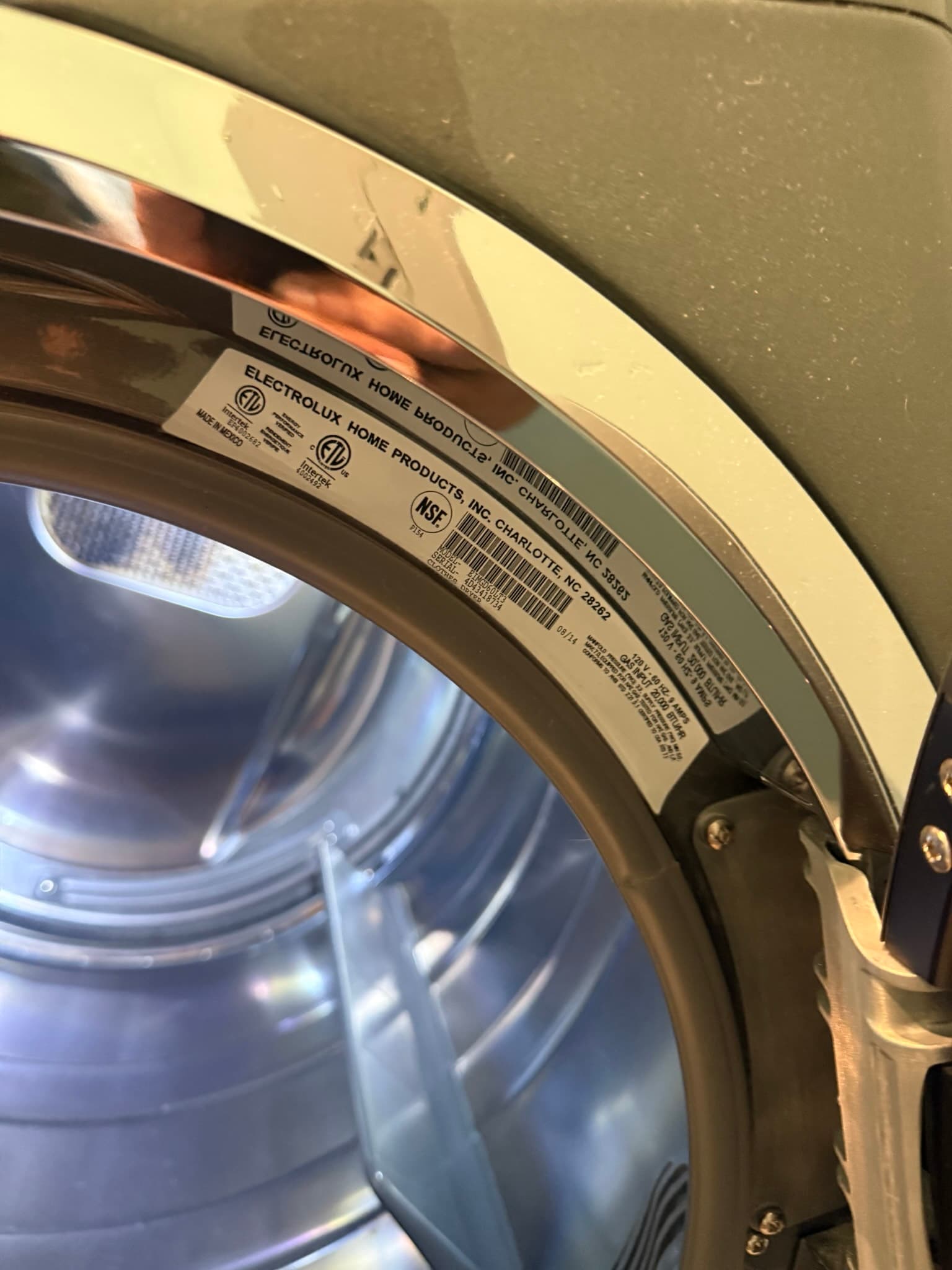 Close-up of the front frame and door area of an Electrolux Home Products electric dryer showing manufacturer labels, NSF certification, and a clean drum interior with intact door seal