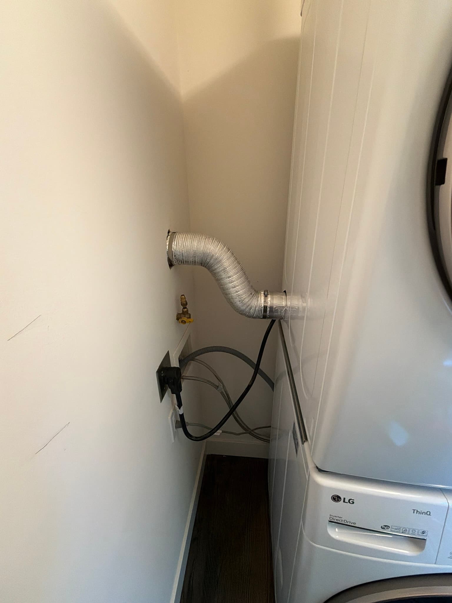 LG dryer connected to the newly installed flexible transition duct running from the wall vent opening to the rear exhaust port, secured with clamps at both ends