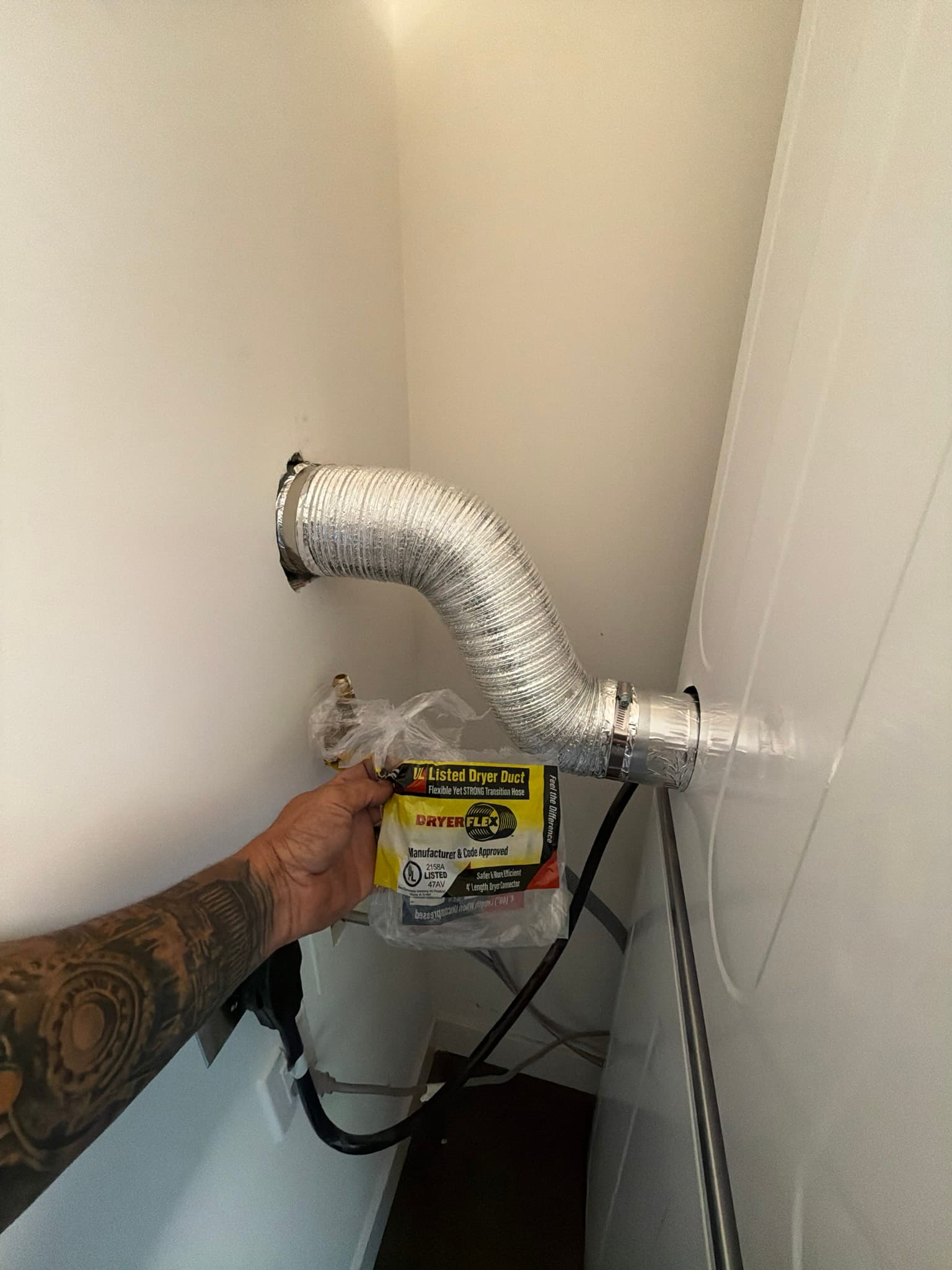 Technician holding the packaging for the new 4 foot DryerFlex transition duct and clamp kit installed on this job