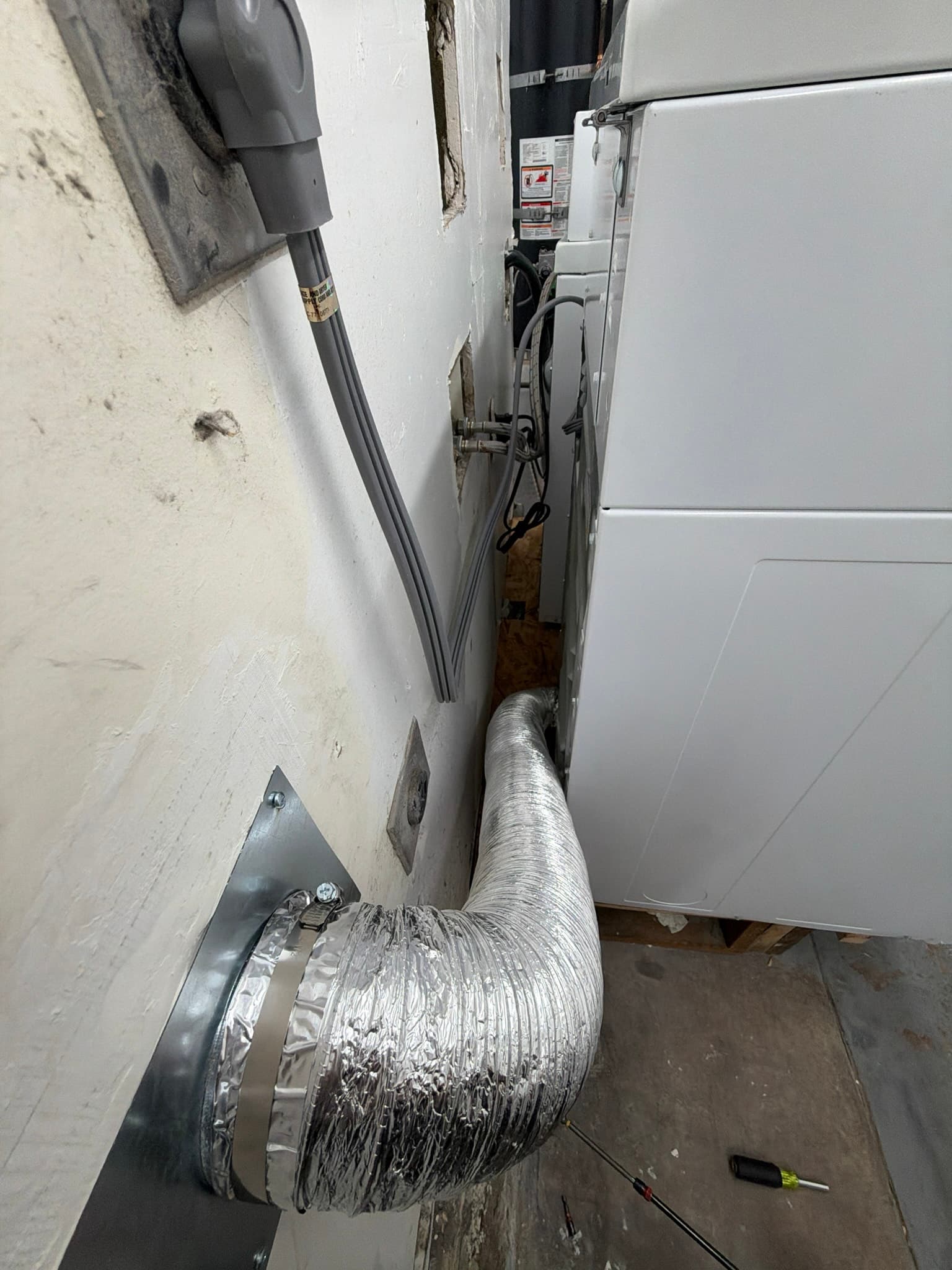 Flexible aluminum transition duct connecting the dryer to a rigid metal wall vent fitting, secured with a hose clamp and sealed with foil tape, with no lint visible along the clean duct run